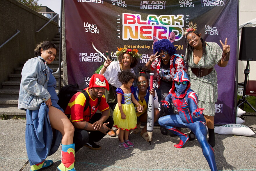 People in colorful costumes pose in front of a banner.