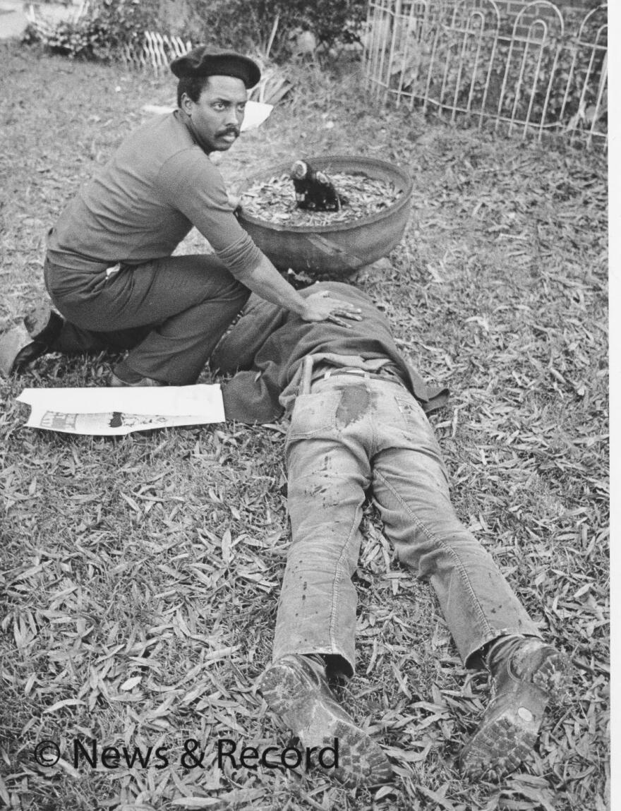 Workers Viewpoint Organization member Nelson Johnson kneels by a victim in the aftermath of the shooting on Nov. 3, 1979. 