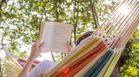 a person lays in a hammock with an open book