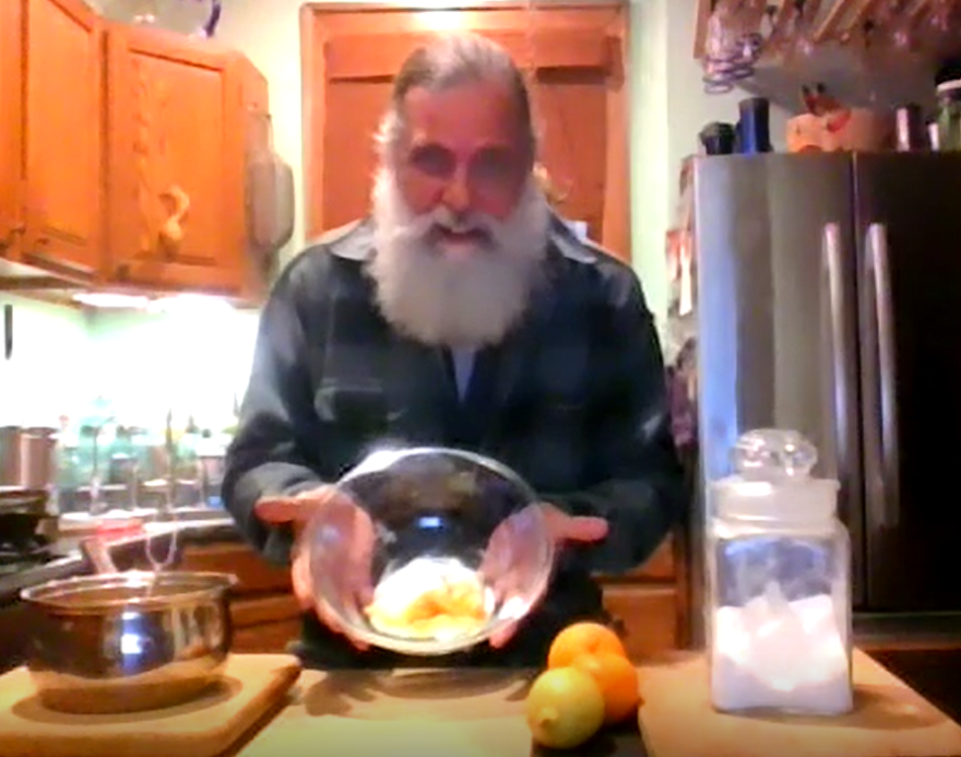 color photo of Jim Bates holding bowl of candied orange peel in his kitchen