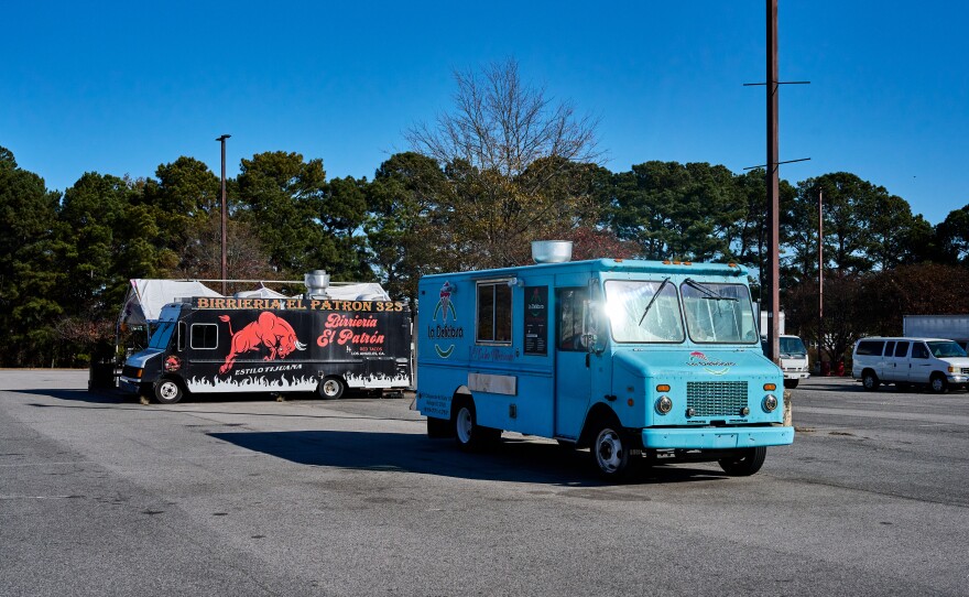 Normally busy food trucks sit empty in the parking lot of a hispanic shopping center.