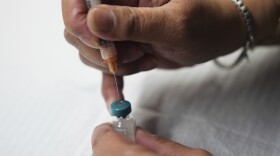 A person prepares a vaccine dose 