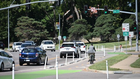 A man riding a bicycle uses a bike lane next to traffic along a busy street. The intersection shows it is located at 39th Street and Gillham Road.