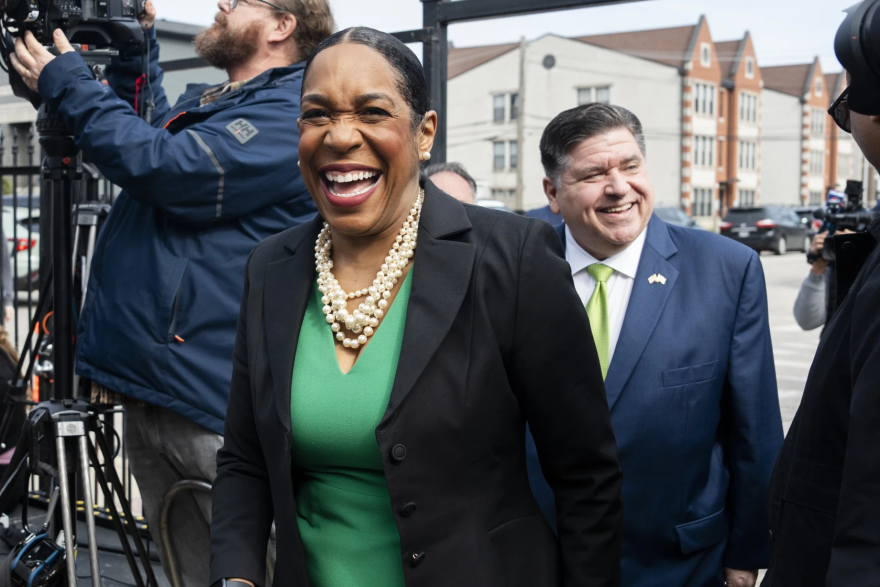 Juliana Stratton, wearing a green dress and black blazer, walks in front of Gov. JB Pritzker. Pritzker is endorsing Lt. Gov. Juliana Stratton’s bid for the U.S. Senate on April 25, 2025.