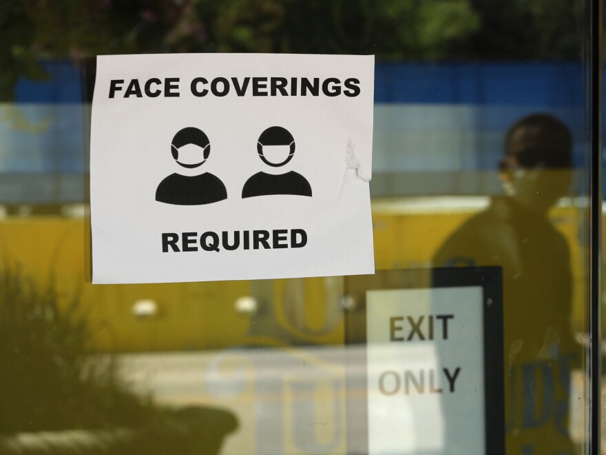 A business in San Antonio posts a reminder about face masks. The city is one of a growing number of localities and states mandating that face coverings be worn in public.