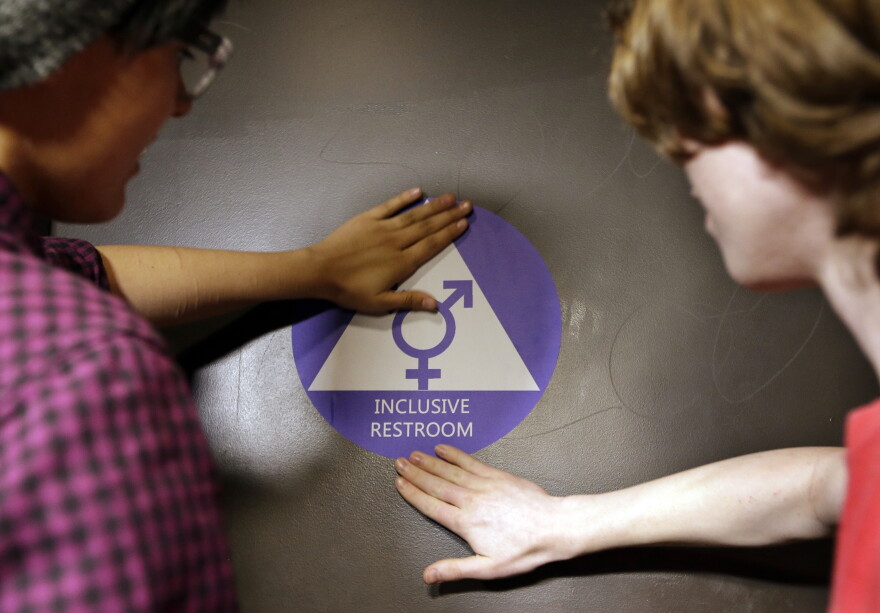 Destin Cramer, left, and Noah Rice place a new sticker on the door at the ceremonial opening of a gender neutral bathroom at Nathan Hale high school Tuesday, May 17, 2016.
