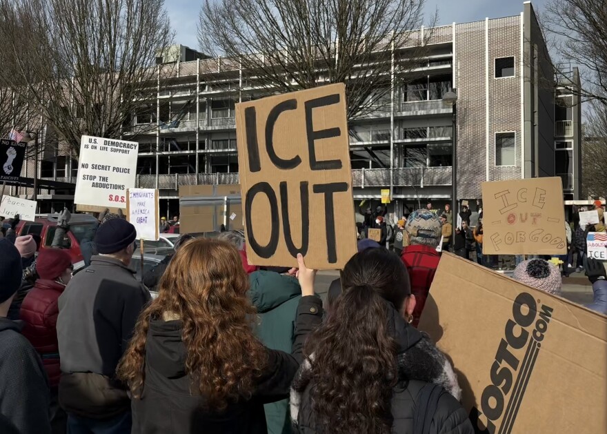 Sophie Gordon and Hazel Fiedler carry homemade signs protesting ICE on January 25, 2026.