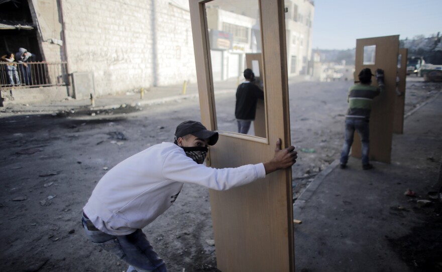 Palestinian stone-throwers take cover behind doors during clashes with Israeli police in Jerusalem on Thursday. For months, the streets of East Jerusalem have been tense, with frequent clashes between police and Palestinians.