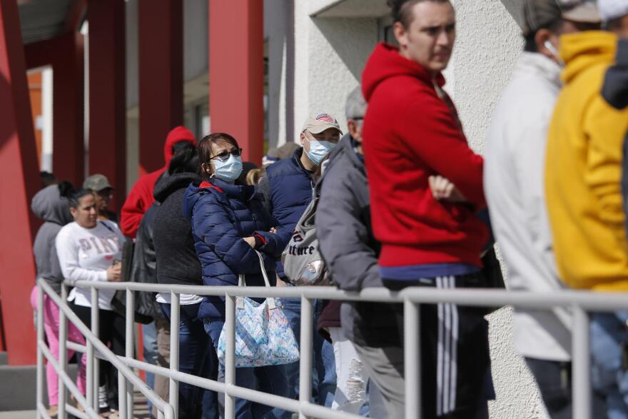 In this March 17, 2020, file photo, people wait in line for help with unemployment benefits at the One-Stop Career Center in Las Vegas.