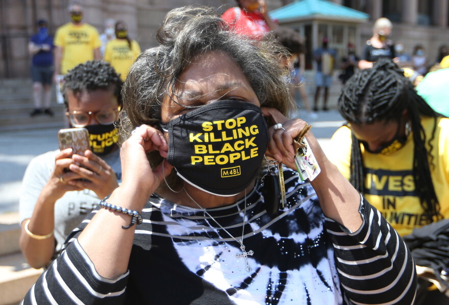 St. Louis Comptroller Darlene Green puts on a mask during a Juneteenth celebration at St. Louis City Hall, where people called on the city to close the Workhouse and help Black transgender people.