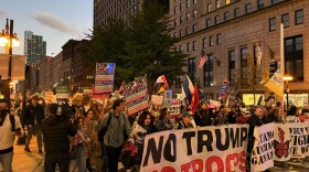A group of protesters carrying signs walk down a street. 