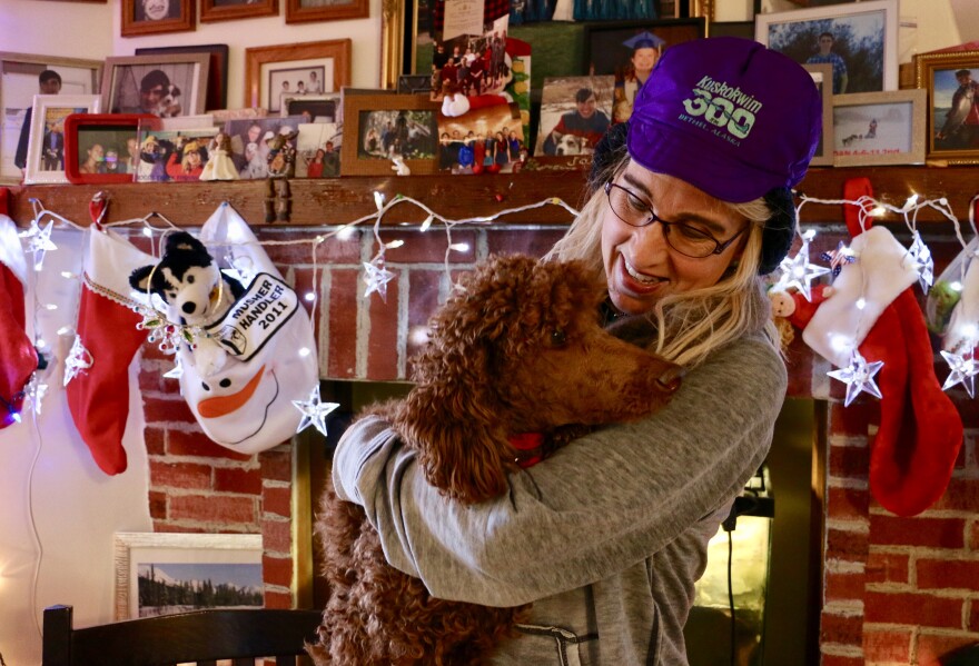 Jackie Klejka wears her signature K300 hat while holding her indoor dog Jersey inside her Bethel home, which is heavily decorated with sled dog paraphernalia. Klejka has been coordinating the K300 veterinary program since 1993.