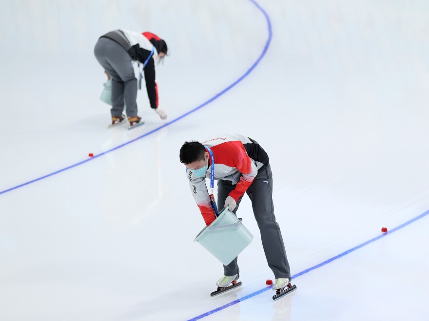 Track staff place lane markers on the ice ahead of the Women's 3000m on day one of the Beijing 2022 Winter Olympic Games.