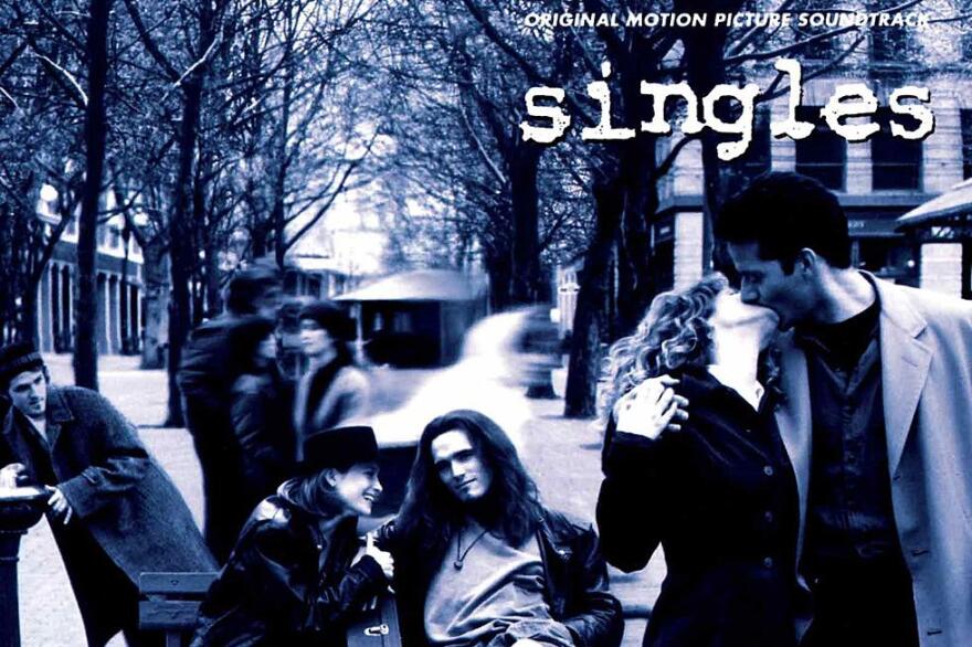 One couple sits on a bench while another kisses.