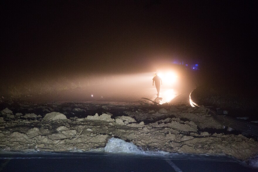 A state policeman inspects the mudslide covering route 39 west of Richwood.