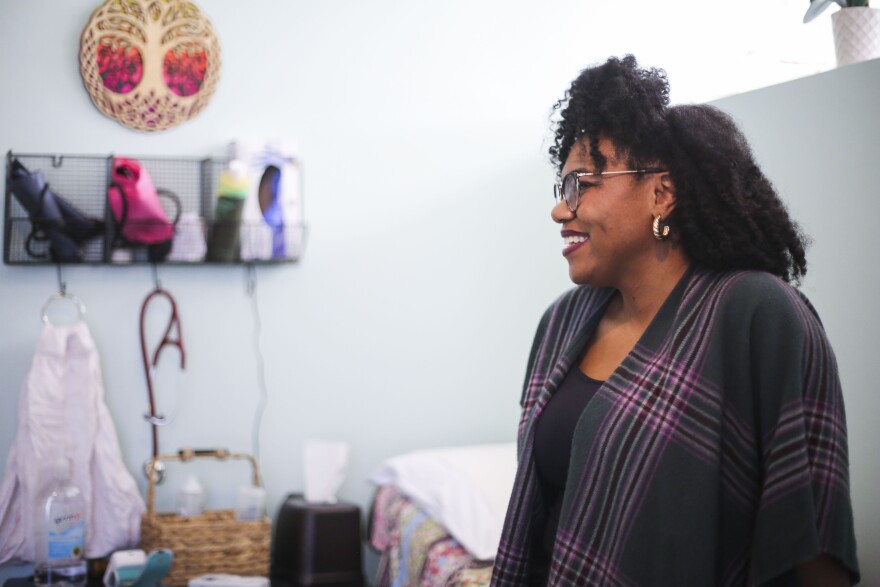 Krystal Brown, Certified Nurse Midwife, leans on the examine bed while waiting for patient.