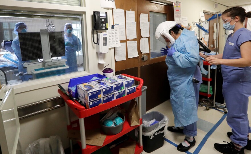 A medical worker is assisted into personal protective equipment on May 8 before stepping into a patient's room in the COVID-19 intensive care unit at Harborview Medical Center in Seattle.