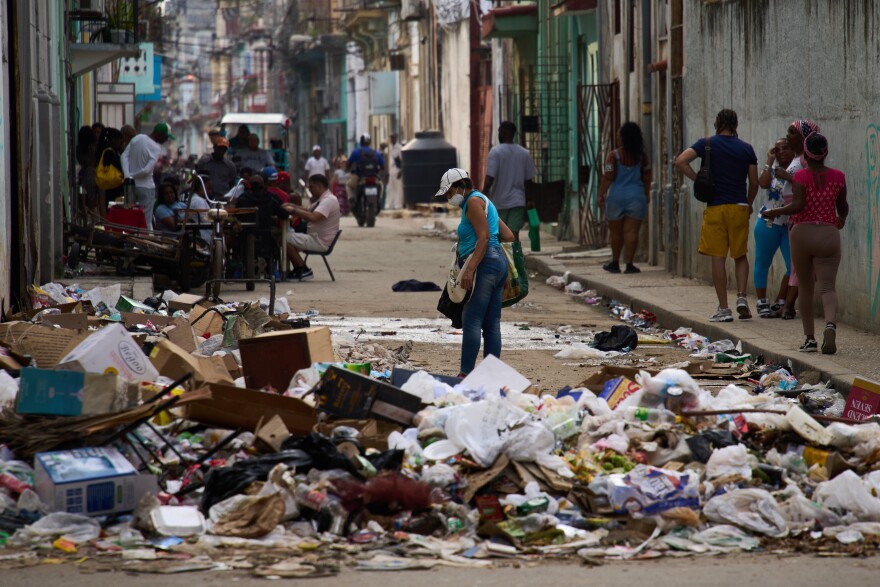 Pedestrians on Feb. 17, 2026, walk past mountains of trash gathering on the streets of Havana. Severe fuels shortages have made it harder for the government to collect and transport the trash.
