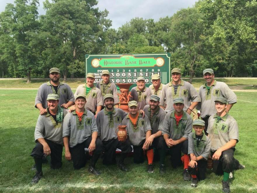 The Walker Tavern Wheels pose in their uniforms in front of a scoreboard 