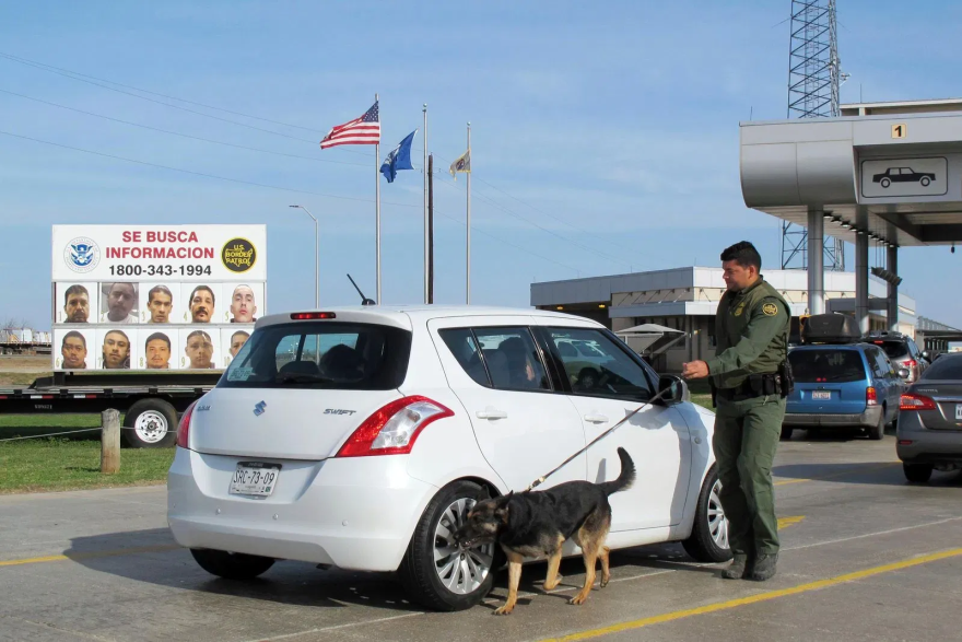 A Border Patrol agent uses a dog to inspect a car waiting to pass through the Laredo North vehicle checkpoint in Laredo, Texas, on Friday, February 2, 2018. 