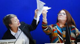 Canvassing Board chair Judge Betsy Benson, left, and board member Judge Deborah Carpenter-Toye, right, show political lawyers one of the ballots that was damaged during the recount that will need to be duplicated and then recounted, at the Broward County Supervisor of Elections office during a recount on Wednesday. (AP Photo/Wilfredo Lee)