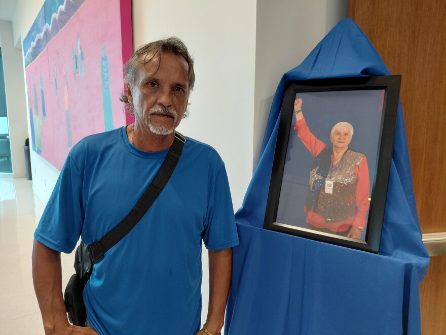 Pedro Felix stands next to a photo of Sylvia Collins, who was his neighbor for 14 years at The Clyde apartments in Oak Cliff. He showed up to honor Collins.