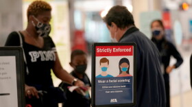 A sign advises passengers to wear face masks as they approach a security checkpoint at Miami International Airport, Wednesday, Nov. 25, 2020, in Miami.