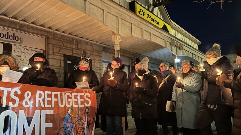 People hold candles and a banner at a Jan. 27, 2026, vigil outside El Potro Mexican Restaurant in downtown Brainerd.