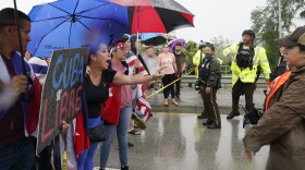 Cuban Protesters with signs and umbrellas coming to face to face with police in Miami.