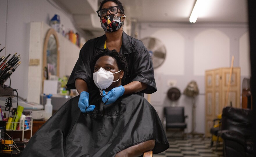 Renee McFarlin prepares her client, Jacob, for his dredlock retwist. McFarlin completes a thorough cleaning before each new client enters her Ansonia salon, Lisa's Beauty & Barber, and wears a mask throughout the appointment. 