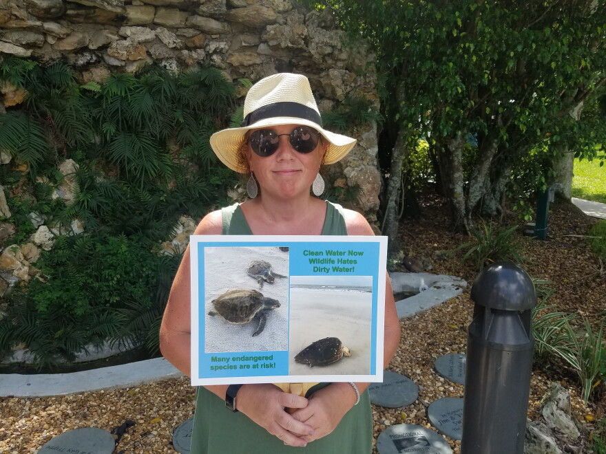 Fort Myers Beach resident Jennifer Rusk held a sign with pictures showing dead turtles she has found while walking on the beach. 