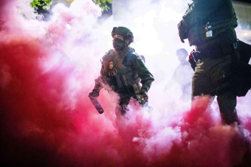 Police and federal officers deploy gas canisters to disperse protesters near a U.S. Immigration and Customs Enforcement facility in Portland, Ore. on Oct. 5, 2025. (Ethan Swope/AP)
