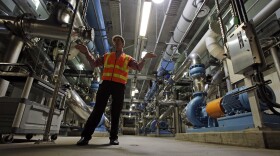 A worker stands in front of a water filtration system at a water treatment plant.