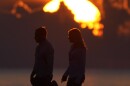 FILE - A couple walks along a jetty as the sun rises over the Atlantic Ocean, Wednesday, June 28, 2023, in Bal Harbour, Fla.