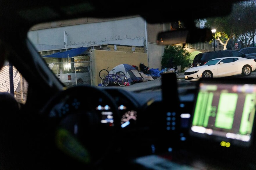 A San Diego Police Department patrol vehicle drives past an encampment in downtown San Diego on March 22, 2024.