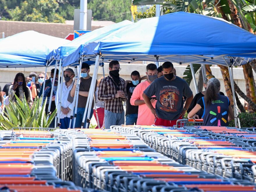 People wearing face coverings wait to shop at Walmart on Wednesday in Burbank, Calif. The state has seen more than 425,000 cases, including more than 12,000 new cases on Wednesday.