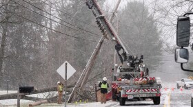 Utility crew workers replace a power pole snapped in two when high winds downed a tree in Sagamore Hills, Ohio, Monday, Dec. 29, 2025. (AP Photo/Sue Ogrocki)