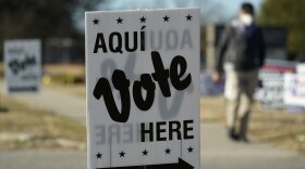 A man passes an early voting poll site, Monday, Feb. 14, 2022, in San Antonio. Early voting in Texas began Monday. (AP Photo/Eric Gay)