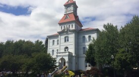 The Benton County courthouse, a tall white building with an American flag placed on top, on a sunny day.