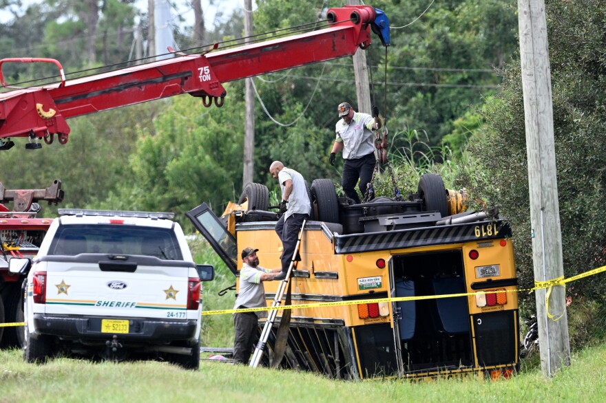 A vehicle recovery crew work to right an overturned school bus after a fatal collision, Monday, Oct. 5, 2026, in Winter Haven, Fla.