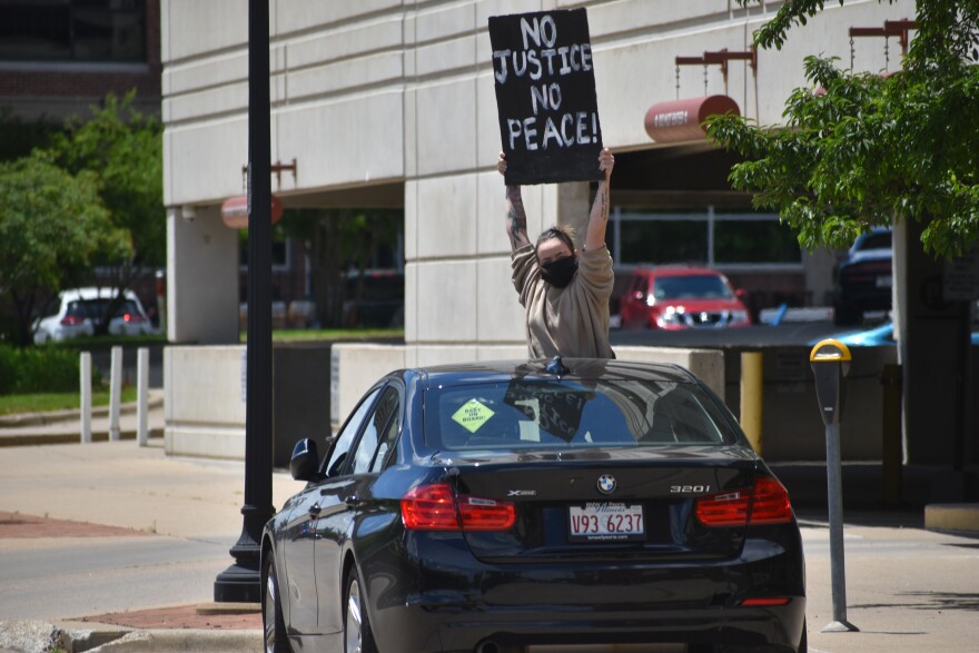 A protestor holds up a sign from a parked car on Water Street in Peoria, May 30, 2020.
