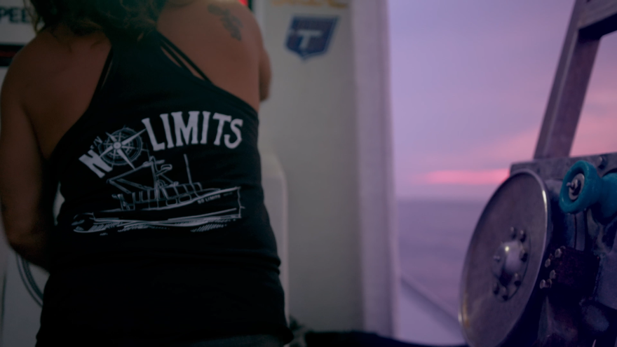 A woman on a boat wears a t-shirt with a graphic of a boat and the words "NO LIMITS"