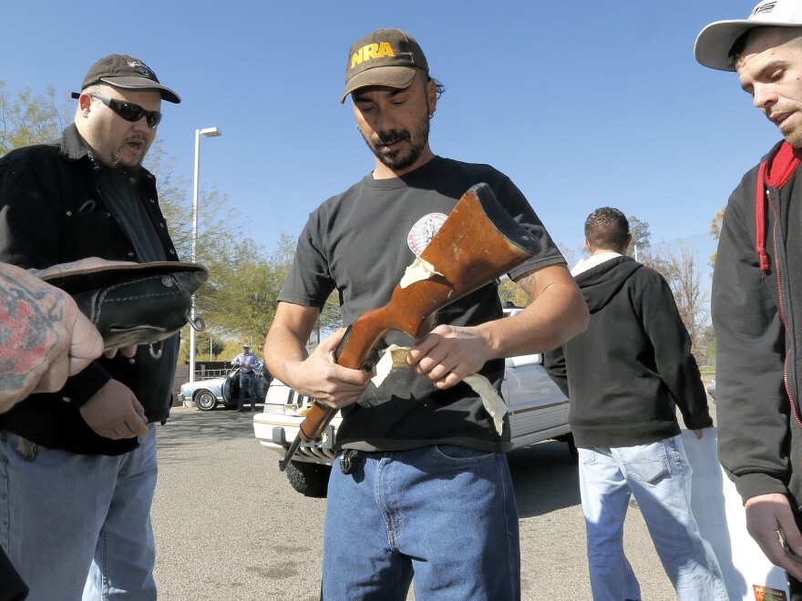 Gun buyers inspect their purchases outside a police station in Tucson, Ariz., on Tuesday. About a dozen buyers offered cash to sellers in the parking lot of a police station where a city councilman had set up a gun buyback program.
