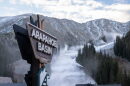 The Arapahoe Basin Ski Area sign in front of a mountain that's beginning to be covered in snow.