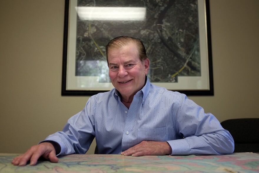 A man sits in front of a map of.