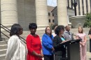 Debbie Watts Robinson stands on the far left of the image, smiling at Montgomery County Commissioner Mary McDonald as Dayton Mayor Shenise Turner-Sloss speaks at a podium