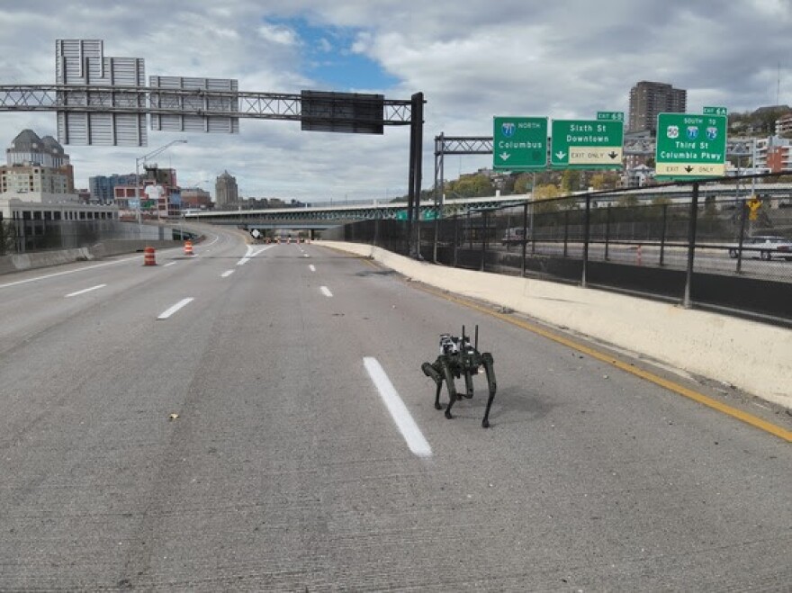 A robot dog trots along a bridge inspecting damage from a recent fire.