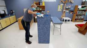 Des Moines Public Schools custodian Cynthia Adams cleans a desk in a classroom at Brubaker Elementary School, Wednesday, July 8, 2020, in Des Moines, Iowa. Getting children back to school safely could mean keeping high-risk spots like bars and gyms closed. That's the latest thinking from some public health experts. (AP Photo/Charlie Neibergall)