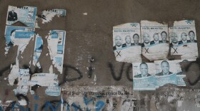 Old campaign posters from the 2016 presidential election cover a wall along a sidewalk in Port-au-Prince, Haiti, Monday, March 2, 2026.