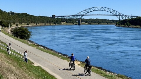Cyclists ride the Canal Service Road, also called the bike path, on the north side of the Cape Cod Canal, heading toward the Sagamore Bridge, September 15, 2022.